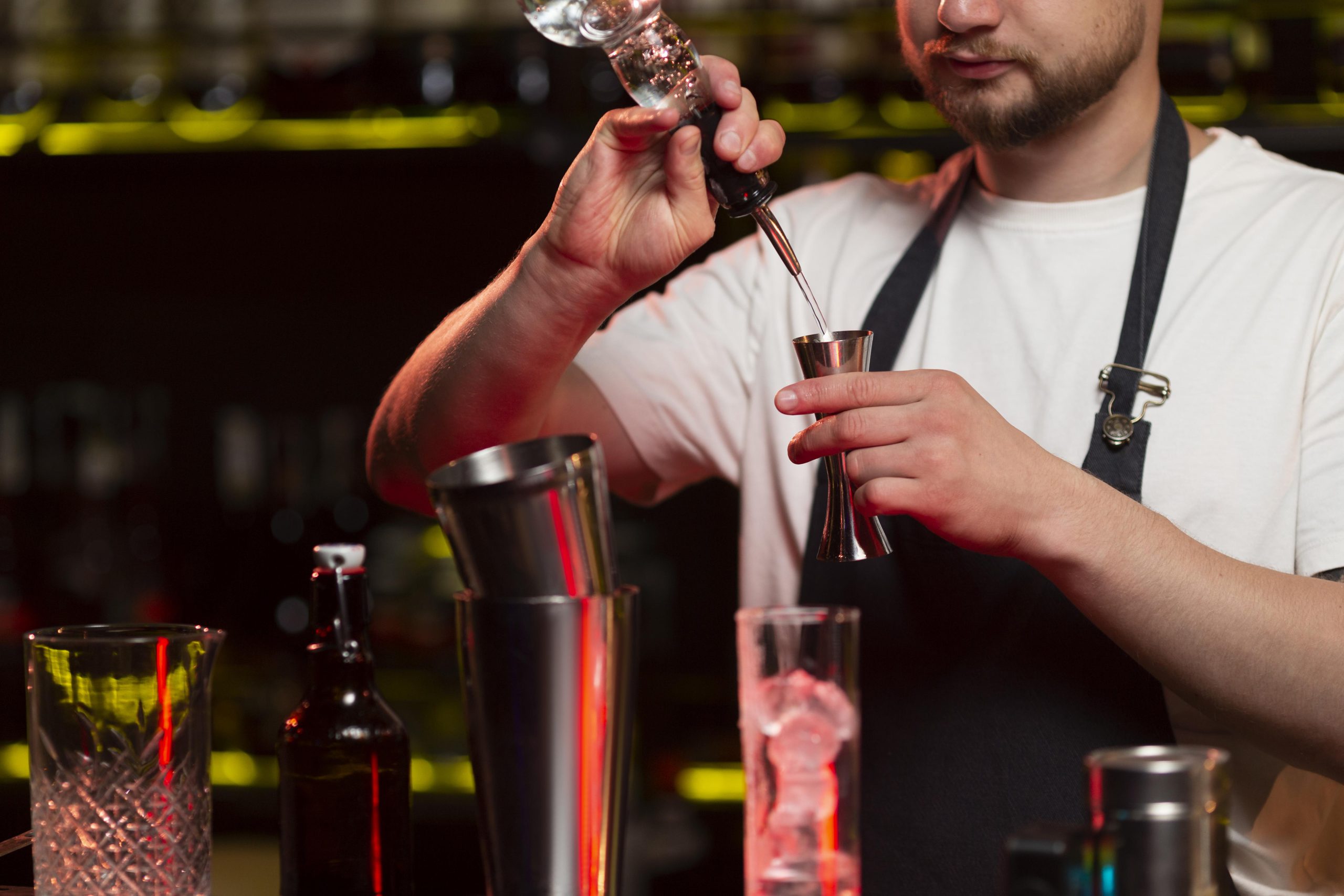 Mężczyzna w ciemnym pomieszczeniu robi drinki za pomocą shakera - kursy barmańskie