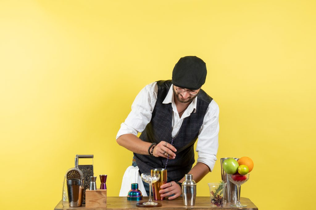 elegancko ubrany mężczyzna przygotowuje drinki na stanowisku - kursy barmańskie